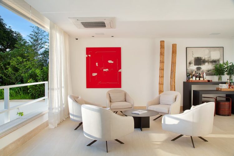 Um quadro vermelho na parede, em frente, um circulo com cinco cadeiras e uma mesa baixa no meio.