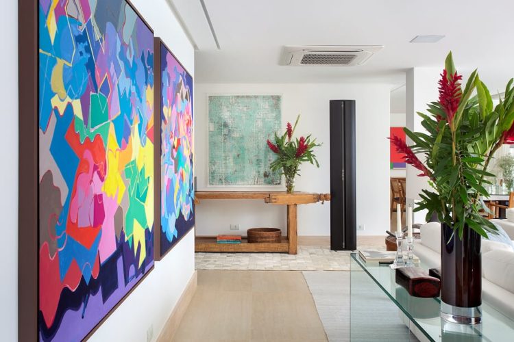 Sala com quadro colorido na parede e em frente aparador de vidro