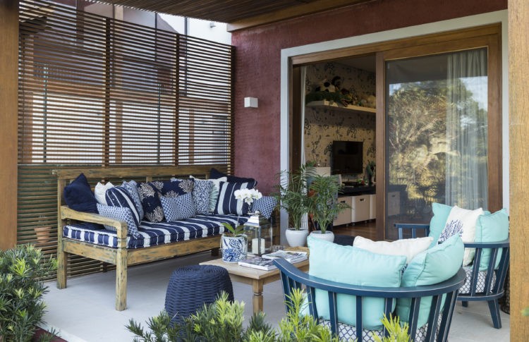 "Lifestyle" descontraído dita o décor, varanda com banco em madeira e cadeiras verdes
