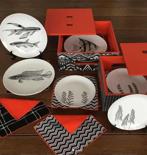 Caixa vermelha embalando pratos rasos em porcelana com peixes pintado a mão.