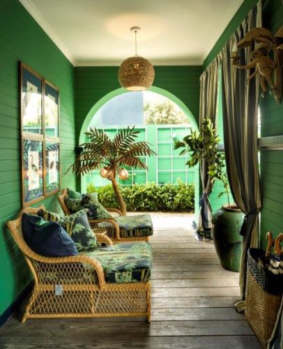 Varanda com as paredes pintadas de verde, duas cadeiras chaise em vime e tecido estampado