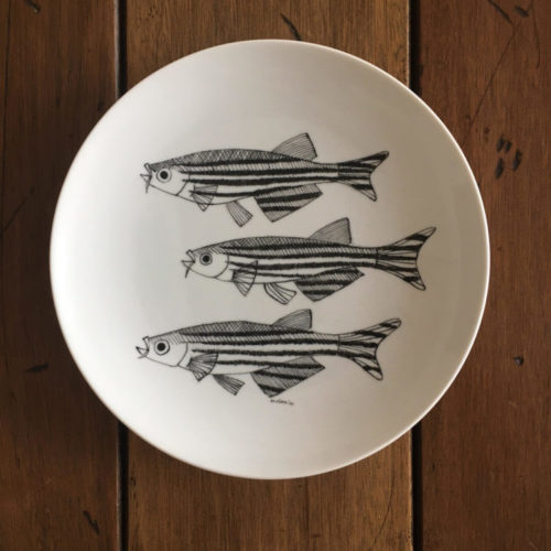 Prato de porcelana redondo com tres peixes pintados na cor preta