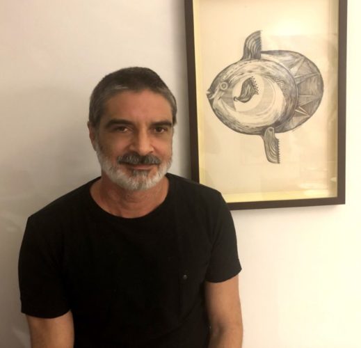 Foto do artista Gustavo Portela, de camiseta preta e barba