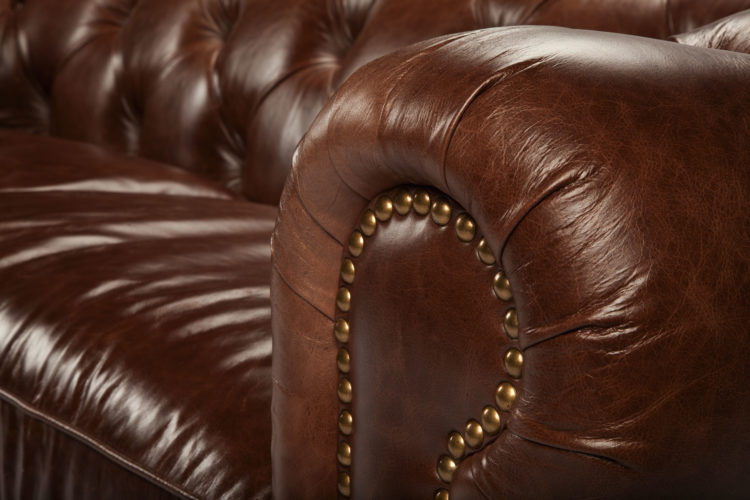 sofá Chesterfield, aquele grande, confortável e capitonê (ou botonê, cheio de botõezinhos), em couro marrom e braços arredondados com tachas 