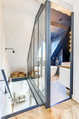 Escada que da acesso ao banheiro com banheira e uma janela. Esquadrias azuis