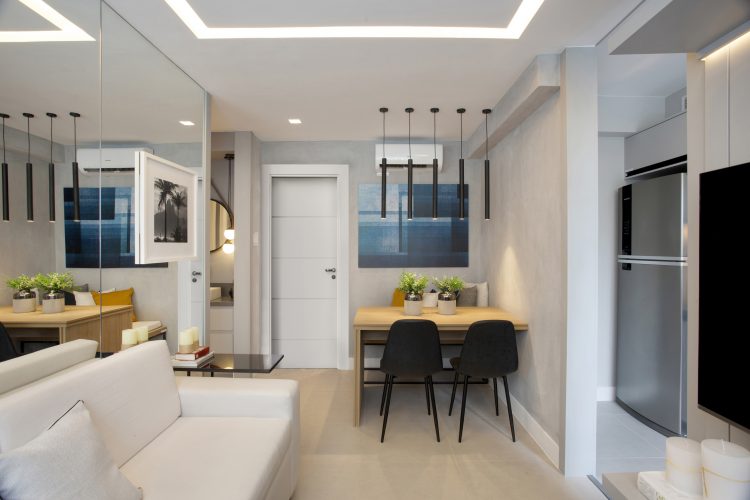Apartamento pequeno com os ambientes integrados e a parede de sofá espelhada 
