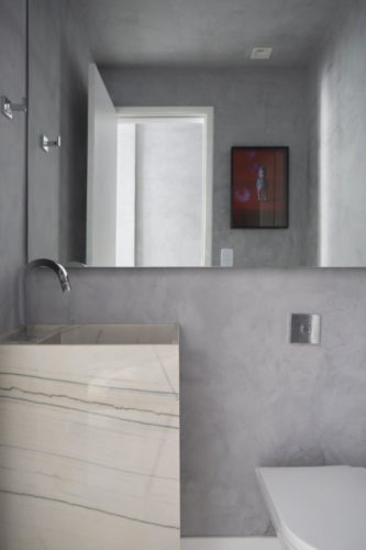 Apartamento compacto - 36m2 muito charmoso conseguiu ter espaço para o lavabo, que tem uma faixa de espelho em na metade de cima da parede e o restante em uma pintura imitando cimento.