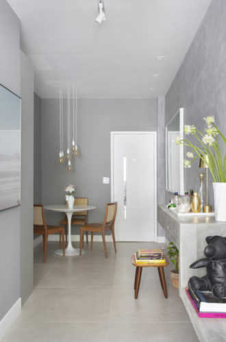 Apartamento pequeno e bem resolvido em Ipanema. Sala estreita com piso em porcelanato claro, paredes na cor cinza imitando cimento