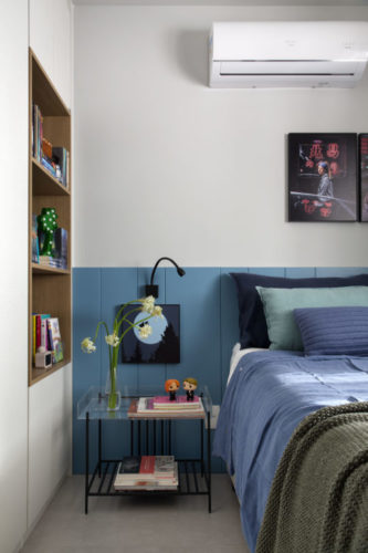 Quarto com cabeceira da cama em madeira pintada de azul e ao lado armário com nichos em madeira