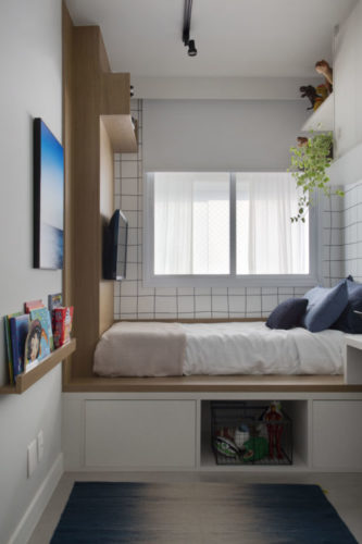 Quarto de menino em um apartamento pequeno, cama em cima de um tablado ato de madeira e embaixo espaço para armazenamento.