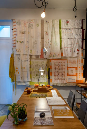 mesa em madeira, parede lateral com varias bandeiras de tecido bordado pendurado.