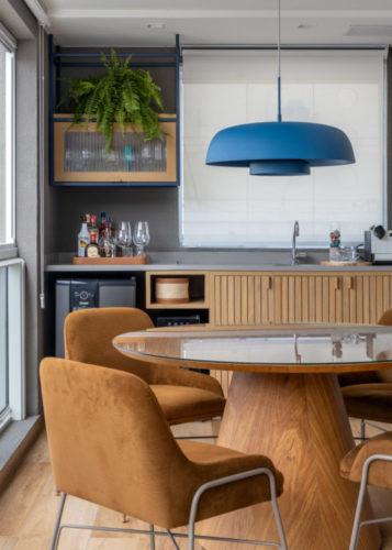 Varanda integrada no apartamento de 90m² na Zona Sul carioca Mesa de jantar redonda, ao fundo bancada com cuba e mini geladeira