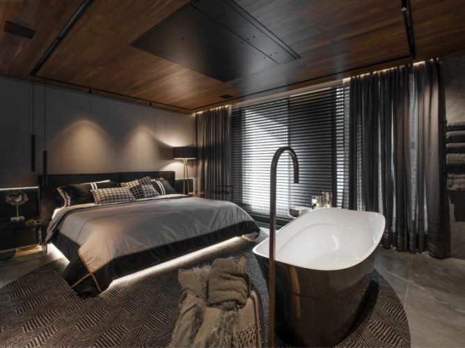Loft com cortinas e persianas pretas, em frente a cama uma banheira