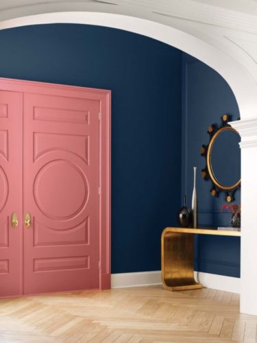 Tendências de cores de tinta para 2022, previsão anual da  Colormix da Sherwin-William. Hall de entrada com a parede pintada de azul, porta de entrada rosa e uma aparador dourado