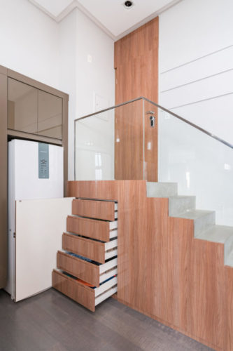 Escada de acesso ao apartamento, ao lado da cozinha, com a parte mais alta cheio de gavetas.