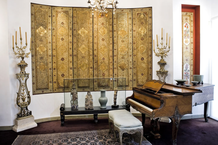 Casa Museu Ema Klabin reabre em São Paulo. Sala de musica com piano, tapeçaria na parede e ao lado, esculturas em madeira