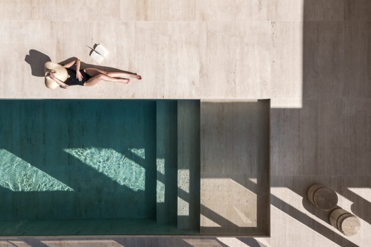 Foto de uma mulher na piscina com o piso revestido em pedra natural