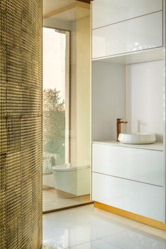 Banheiro separado por uma parede de vidro na cor dourada