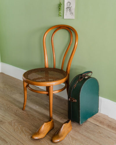 Classica cadeira em madeira em frente a parede pintada de verde.