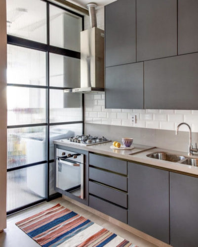 Cozinha com esquadria preta e vidro canelado dividindo espaços 