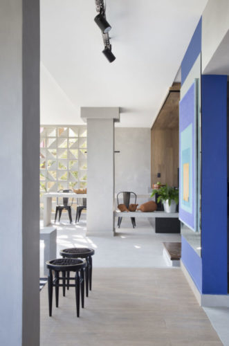 Casa com área gourmet revestida com cimento no piso e paredes, além da mesa e banco