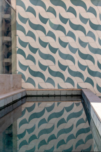 Painel em azulejos na parede de fundo da piscina em uma cobertura no Leblon. Azulejos com desenhos gráficos na cor zul e cru
