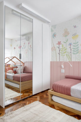Quarto de menina decorado, armários com portas espelhadas, painel na parede na cor rosa e  pra cima, papel de parede florido