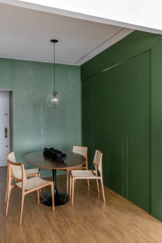 Cozinha separada da sala de jantar por porta modelo camarão pinta de verde folha, permitindo isolar ou integrar os espaços.