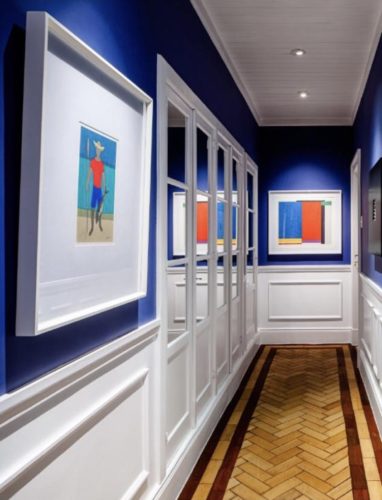 Corredor decorado em um apartamento com protejo do arquiteto Ronald Goulart. Meia parede com boiserie brancas e pra cima pintado em um tom de azul. 