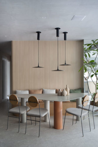 Mesa de jantar com linhas orgânicas, parede revestida de madeira clara atrás.