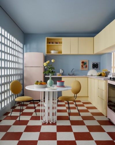 Cozinha com piso xadrez vermelho e bege, armários na cor manteiga