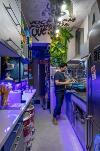 O artista plástico Anderson Thives cozinhando na sua cozinha com grafite no teto e luz azulada