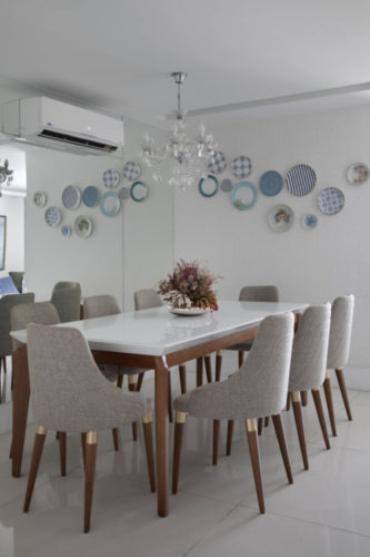 Sala de jantar com parede de fundo espelhada e na outra , um composição de pratos