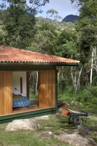 Quarto em uma casa de campo. Portas em madeiras, e quando abertas, espaço bem integrado a natureza
