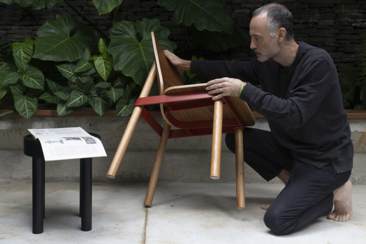 Cadeira com design assinado pelo estúdio Jabutocasa, pé em madeira e uma cinta em alumínio pintado de vermelho