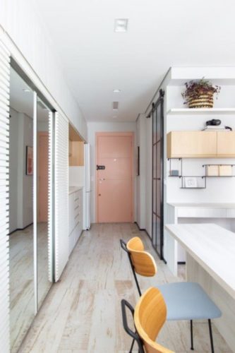 Apartamento de 30m2 de uma jovem solteira, porta de entrada rosa, piso em porcelanato imitando madeira.