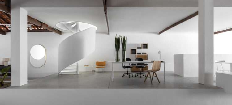 Interior da loja Boobam, paredes na cor branca, piso em cimento bem claro, valorizando o mobiliário em madeira