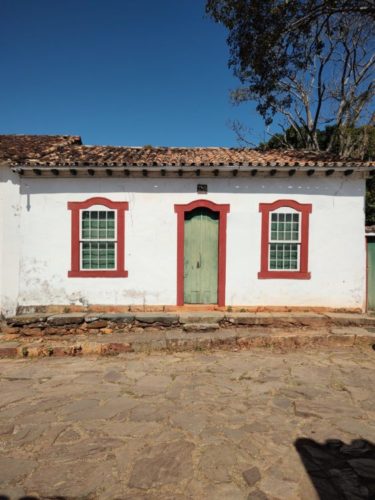 Moradia típica colonial portuguesa-brasileira-mineira, na cidade de Tiradentes. Fachada branca com duas janelas e uma porta ao centro, 