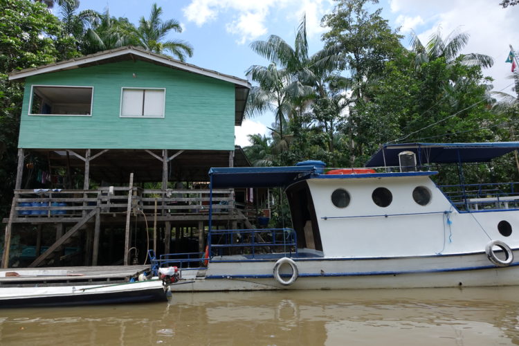 Casa de pescadores em Belém do Pará. em frente ao rio, com barco parado em frente, e alta do piso