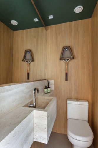 Lavabo com as paredes revestidas em madeira e o teto pintado de verde.