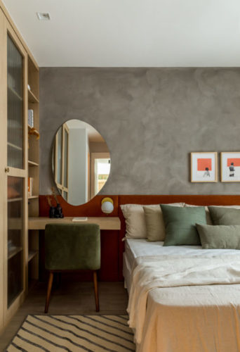Quarto de casal com parede de fundo da cama com pintura imitando cimento e cabeceira da cama em tom terroso 