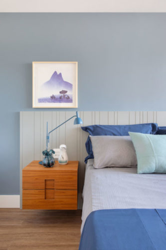 Quarto com parede azul, parede da cama em madeira e mesinha de cabeceira em madeira
