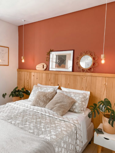 Parede de funda da cama com meia parede em lambri de madeira e pra cima pintada com uma cor terrosa 