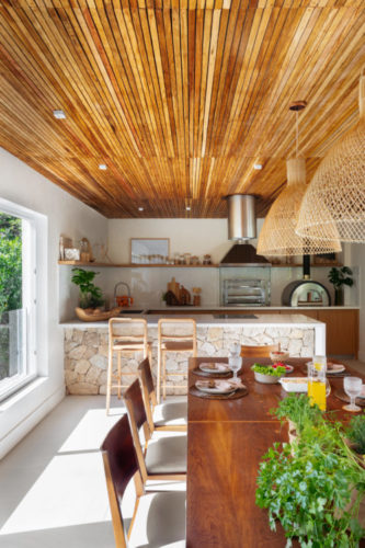 Cobertura em Niterói ganha nova área gourmet, teto revestido em ripas de madeira e balcão em pedra