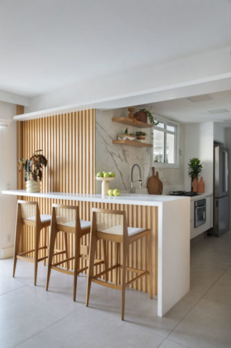 Cozinha integrada a sala, com bancada alta branca e detalhes em madeira ripada