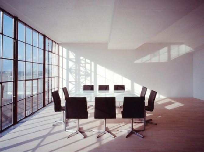 Sala de reunião com uma mesa retangular e varias cadeiras Oxford, do design Arne Jacobsen