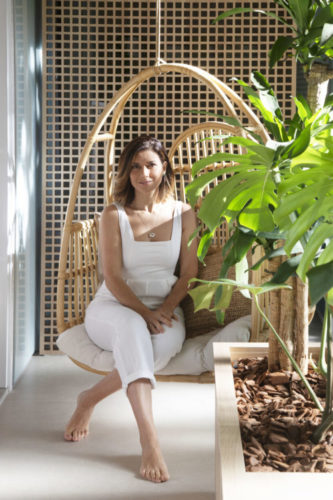 Arquiteta Natália Lemos sentada em uma poltrona de balanço