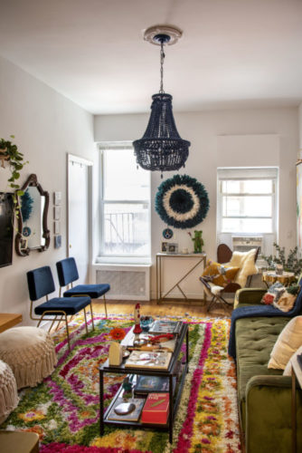 Sala em um apartamento em NY, tapete florido, sofá verde e lustre de cristais azuis