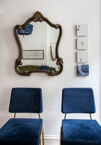 Composição, duas cadeiras azuis, na parede atrás, um espelho antigo 