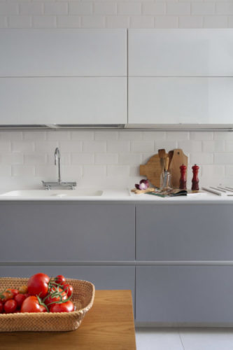 Cozinha com revestimento metro na cor branca, armários superiores branco e embaixo da bancada na cor azul.